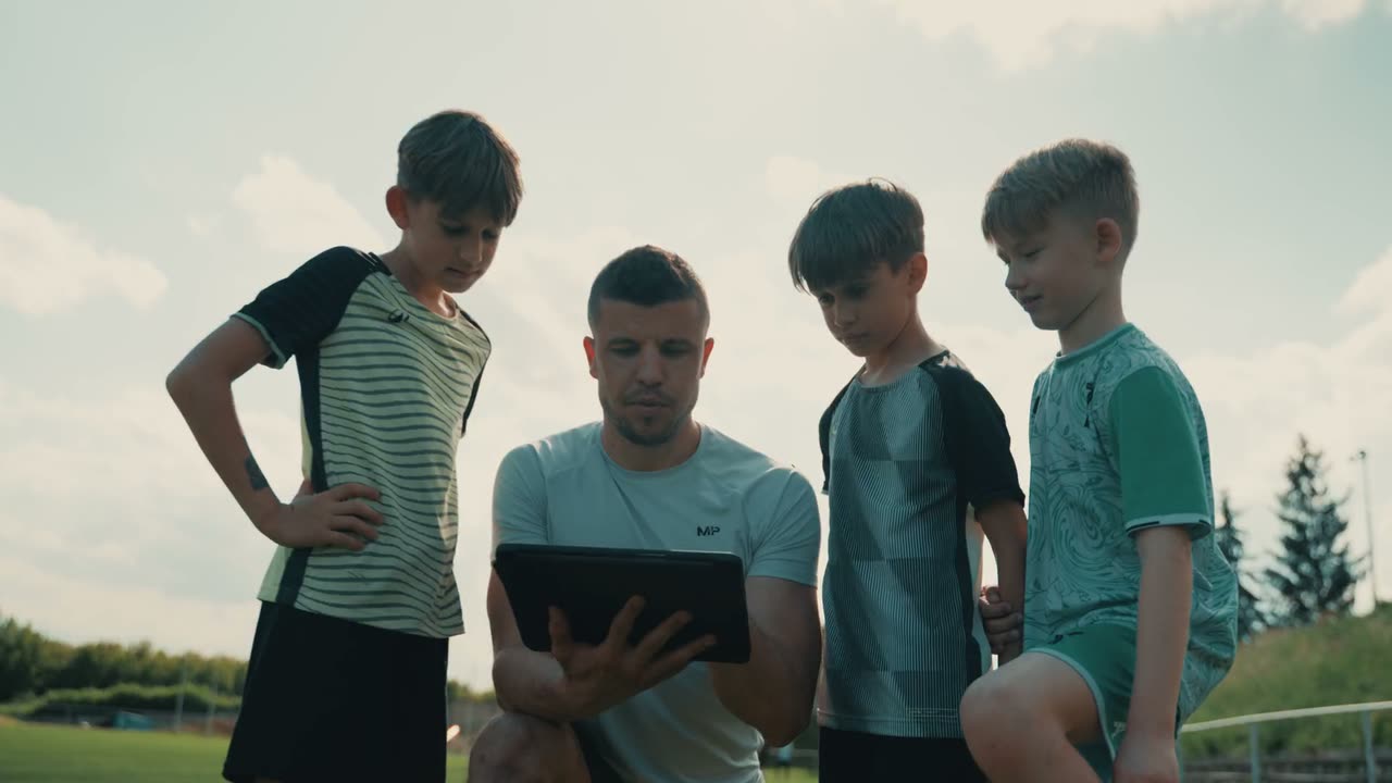 Matúš Marcin vysvetľuje cvičenie skupine mladých hráčov na futbalovom ihrisku.
